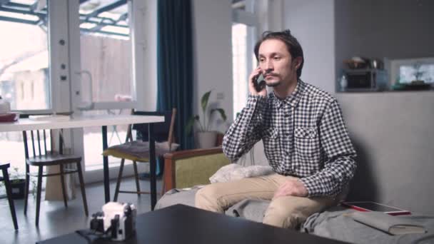 Ten chlap sedí a vzrušeně mluví do telefonu — Stock video