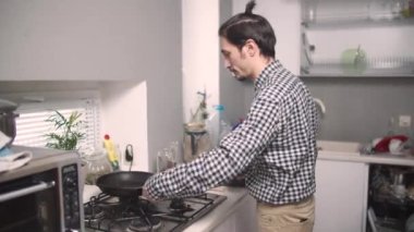 Adam tavada yemek pişiriyor.