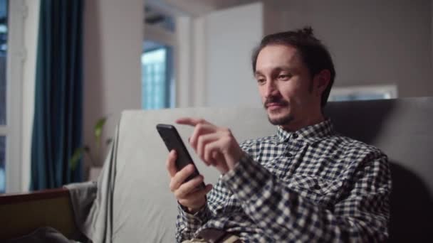 Glad kille sitter med telefonen i handen — Stockvideo