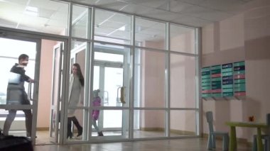 Çocuklu ebeveynler apartmanın koridoruna girerler.