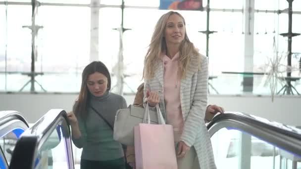 Meninas escalar uma escada rolante em um shopping — Vídeo de Stock