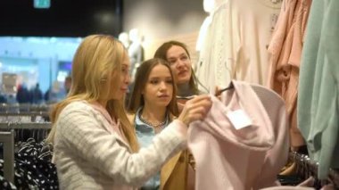 Üç kız arkadaş mağazadan kıyafet seçiyor.