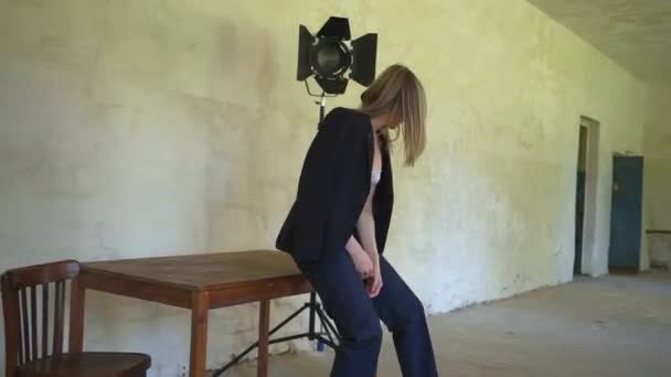 Девушка в черной куртке села на стол — стоковое видео