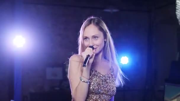 Κορίτσι με γυαλιστερή μπλούζα τραγουδά στο μικρόφωνο — Αρχείο Βίντεο