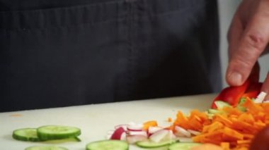 Şef bıçakla kırmızı biberi parçalıyor.