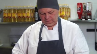 Mutfakta aşçı kırmızı soğan keser.