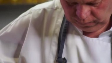 Mavi eldivenli bir şef doğrama tahtasındaki tavuğu kesiyor.