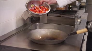 Şef tavaya sebze ekliyor.