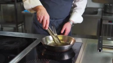 Aşçı kızartma tavasında kızarmış karides hazırlar.