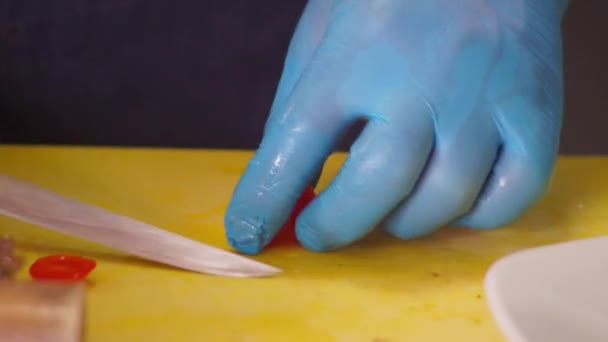 Cozinheiro corta um pequeno tomate vermelho — Vídeo de Stock