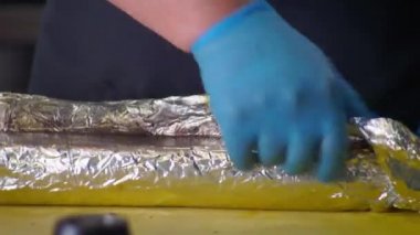 Şef dışarı çıkar ve rulo köfteyi paketten çıkarır.