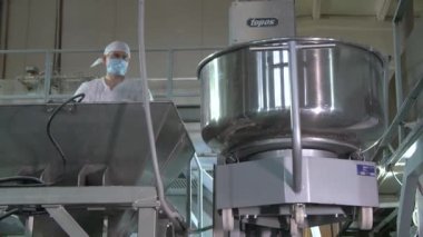 Tek kullanımlık maskeli adam hamur hazırlığını kontrol ediyor.