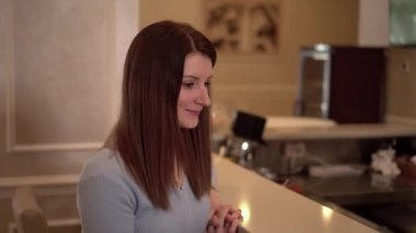 A young brunette with long loose hair is sitting in a restaurant