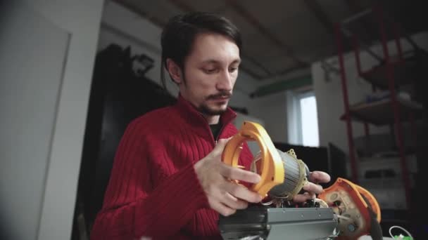 Concentrated engineer in red pullover composes new invention — Stock video