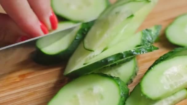 El cuchillo corta el pepino. Cortar verduras en una tabla de cortar de madera. 4k — Vídeos de Stock