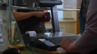 Süpermarkette bir kadın sebze alır. Salatalık, terazide tartılır. 4k