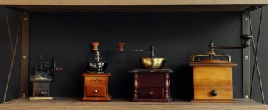 Ahşap duvar rafında antika kahve öğütücüsü ve siyah arka plan.