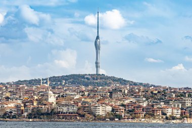 İstanbul 'un ikonik Camlica Kulesi' nin yoğun yerleşim bölgelerinin, tarihi camilerin ve Boğaz rıhtımının üstündeki tepeye hakim olduğu panoramik fotoğrafı. Seyahat, mimari, turizm ve kentsel konsept kullanımı için ideal.