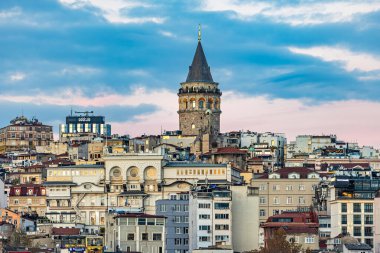 İstanbul şehir manzarasının panoramik fotoğrafı. Renkli tarihi evler ve modern gökdelenlerin üzerinde yükselen ünlü Galata Kulesi. Eski ve yeni mimarinin karışımını yakalar, seyahat, turizm, kültür ve şehir yaşam tarzı temaları için mükemmeldir.