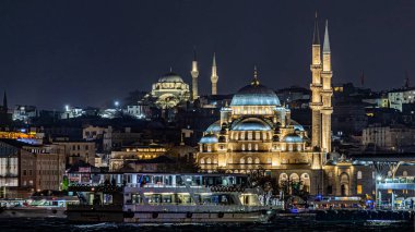 Türkiye 'nin İstanbul kentindeki tarihi bir caminin yüksek çözünürlüklü gece fotoğrafı, aydınlanmış kubbeler ve alacakaranlıkta zarif minareler yer alıyor. Arka planda şehir silueti, seyahat, din, İslam kültürü ve mimari için ideal olan mavi saat sırasında yakalanmıştır..