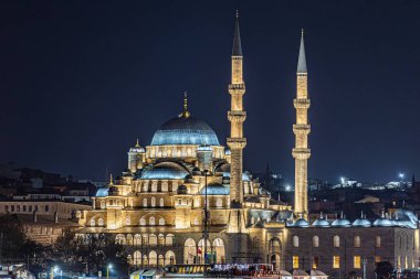 Türkiye 'nin İstanbul kentindeki tarihi bir caminin yüksek çözünürlüklü gece fotoğrafı, aydınlanmış kubbeler ve alacakaranlıkta zarif minareler yer alıyor. Arka planda şehir silueti, seyahat, din, İslam kültürü ve mimari için ideal olan mavi saat sırasında yakalanmıştır..