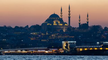 Türkiye 'nin İstanbul kentindeki tarihi bir caminin yüksek çözünürlüklü gece fotoğrafı, aydınlanmış kubbeler ve alacakaranlıkta zarif minareler yer alıyor. Arka planda şehir silueti, seyahat, din, İslam kültürü ve mimari için ideal olan mavi saat sırasında yakalanmıştır..