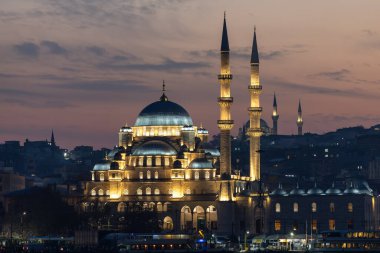 Türkiye 'nin İstanbul kentindeki tarihi bir caminin yüksek çözünürlüklü gece fotoğrafı, aydınlanmış kubbeler ve alacakaranlıkta zarif minareler yer alıyor. Arka planda şehir silueti, seyahat, din, İslam kültürü ve mimari için ideal olan mavi saat sırasında yakalanmıştır..
