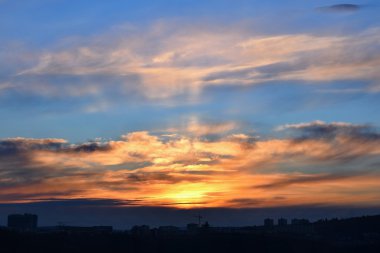 Şehrin üzerinde gün batımı. Gökyüzü bulutlar ve şehir manzarası ile.
