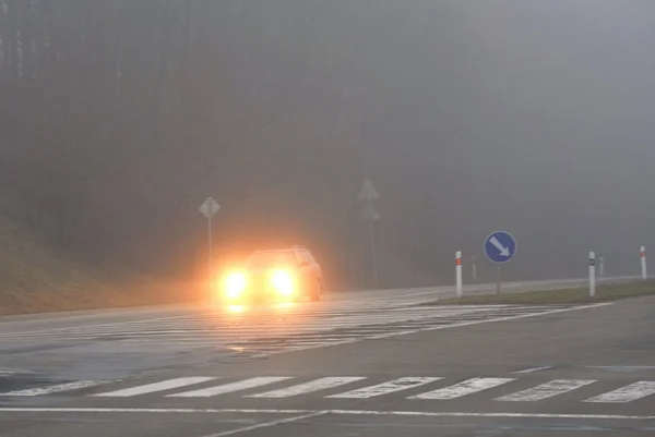 Auta v mlze. Špatné zimní počasí a nebezpečná automobilová doprava na silnici. Lehká vozidla v mlze. — Stock fotografie