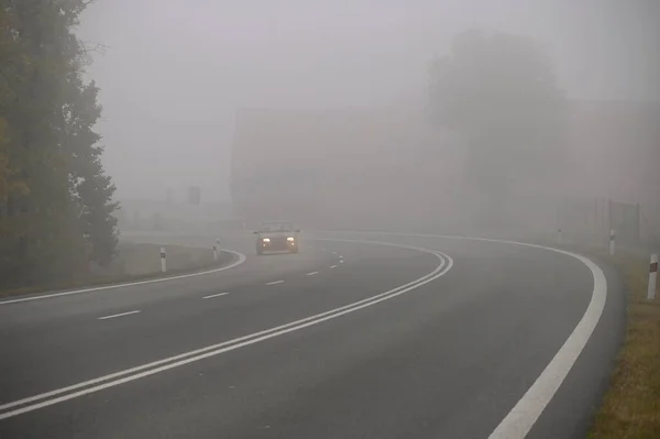 Cars in the fog. Bad winter weather and dangerous automobile traffic on the road. Light vehicles in fog.