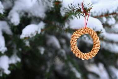Karlı bir Noel ağacında samandan yapılmış güzel doğal Noel süslemeleri. Kış doğası tatil için açık hava arka planı.