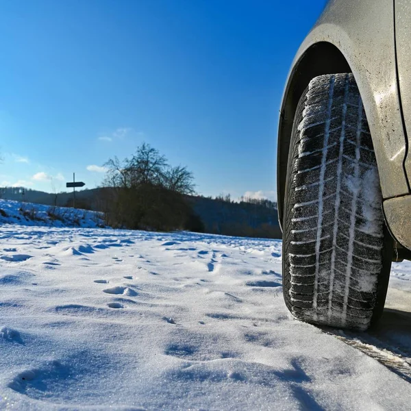 Car in winter in the snow. Winter tires. Winter landscape with sun and blue sky in the background.