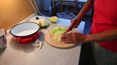 Mutfakta sebze doğrayan ve hazırlayan bir kadın. Yemek ve yemek hazırlama kavramı.