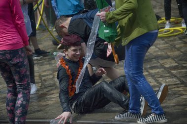 Lviv, Ukrayna - 2 Mayıs 2016: Pazartesi günü Paskalya 'dan sonra belediye binasında kutlama suyu dökülüyor. Mutlu çocuk kızın üzerine su döktü..