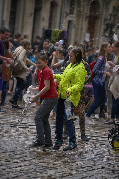 Lviv, Ukrayna - 2 Mayıs 2016: Pazartesi günü Paskalya 'dan sonra belediye binasında kutlama suyu dökülüyor. Mutlu çocuklar birbirlerine su dökerler..