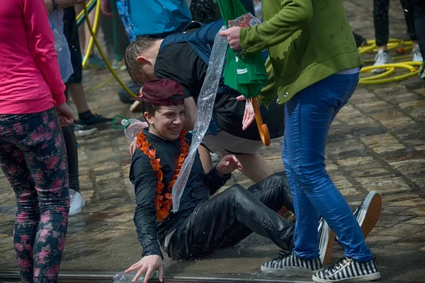 Lviv, Ukrayna - 2 Mayıs 2016: Pazartesi günü Paskalya 'dan sonra belediye binasında kutlama suyu dökülüyor. Mutlu çocuk kızın üzerine su döktü..