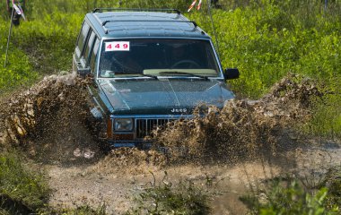 Off-road vehicle brand Jeep Cherokee overcomes a pit of mud clipart