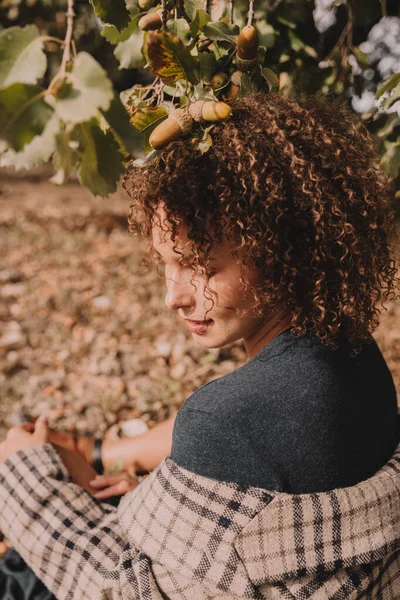 Chica con el pelo rizado bajo un roble. Imagen De Stock