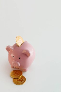İzole edilmiş beyaz arka planda bitcoin paraları olan domuz kumbarası