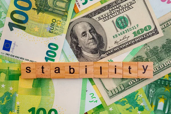 STABILITY nscription on wooden cubes on the texture of us dollars and euro banknotes