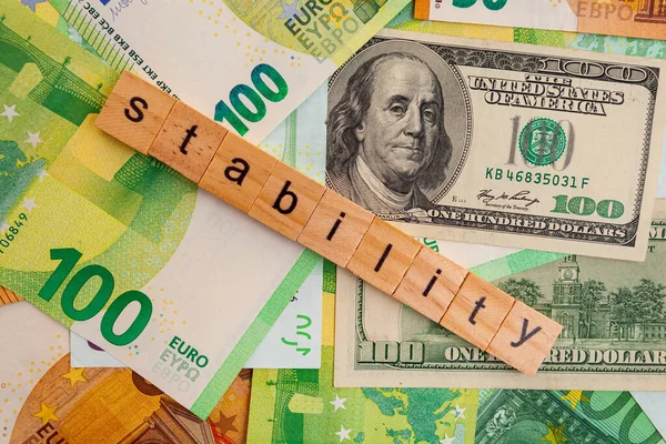 STABILITY nscription on wooden cubes on the texture of us dollars and euro banknotes