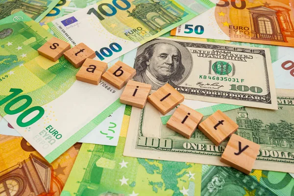 STABILITY nscription on wooden cubes on the texture of us dollars and euro banknotes