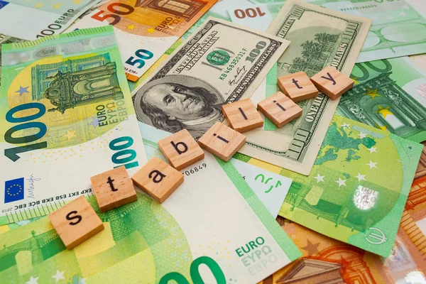 STABILITY nscription on wooden cubes on the texture of us dollars and euro banknotes