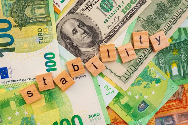 STABILITY nscription on wooden cubes on the texture of us dollars and euro banknotes