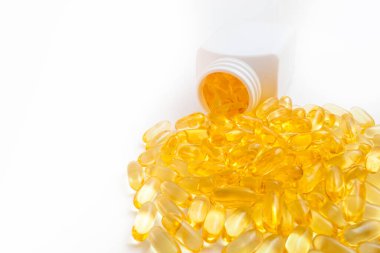 Omega 3 hapları beyaz arka planda kavanozdan dökülüyor.