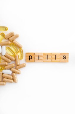 Farklı hapların beyaz arka planında tahta küplere kazınmış yazıtlar.