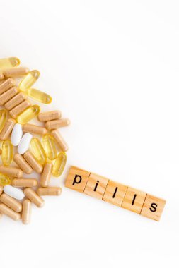 Farklı hapların beyaz arka planında tahta küplere kazınmış yazıtlar.