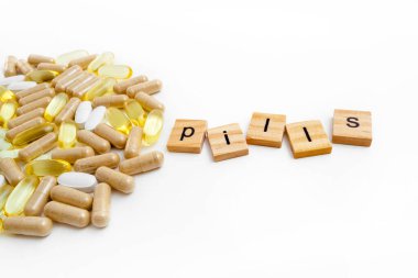 Farklı hapların beyaz arka planında tahta küplere kazınmış yazıtlar.