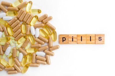 Farklı hapların beyaz arka planında tahta küplere kazınmış yazıtlar.