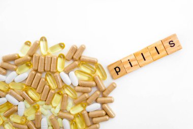 Farklı hapların beyaz arka planında tahta küplere kazınmış yazıtlar.